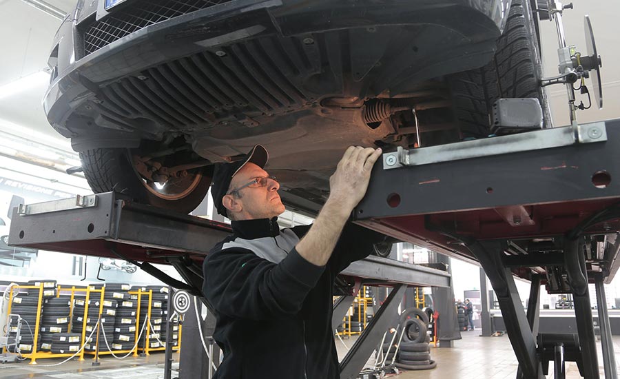 Un homme travaille dans le secteur automobile, effectuant probablement des réparations ou des travaux d'entretien sur une voiture. Il porte des vêtements adaptés aux tâches d'ingénierie, reflétant le rôle du technicien dans la manipulation des machines.
