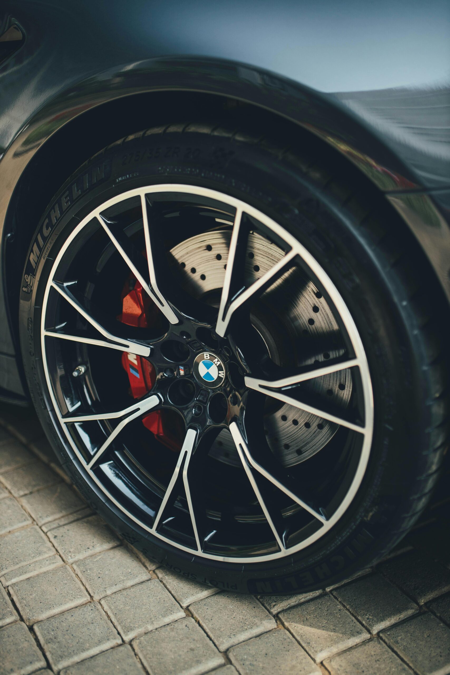 L'image présente un gros plan d'un pneu BMW, mettant en valeur ses détails complexes, tels que la sculpture de la bande de roulement et la jante en alliage. Ce composant lié au transport est fabriqué en caoutchouc synthétique et met en valeur des aspects du design automobile. Ce pneu est destiné à être installé sur un véhicule stationné, soulignant ainsi son rôle dans les déplacements terrestres.